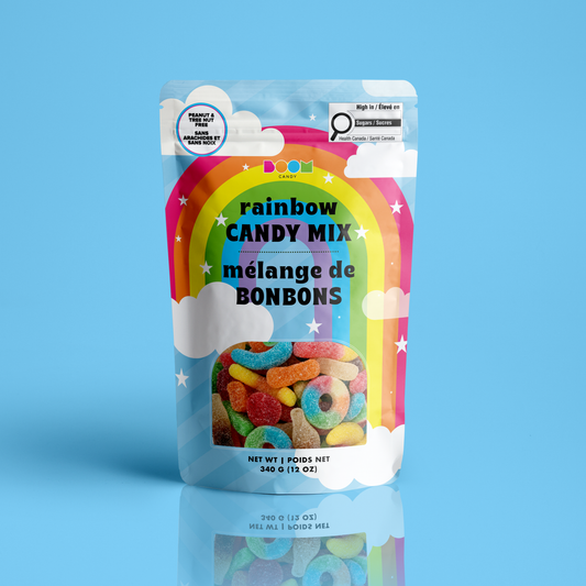 A stand-up pouch of Rainbow Candy Mix by Boom, featuring a colorful rainbow graphic and a clear window showing assorted gummy candies inside, set against a solid light blue background.