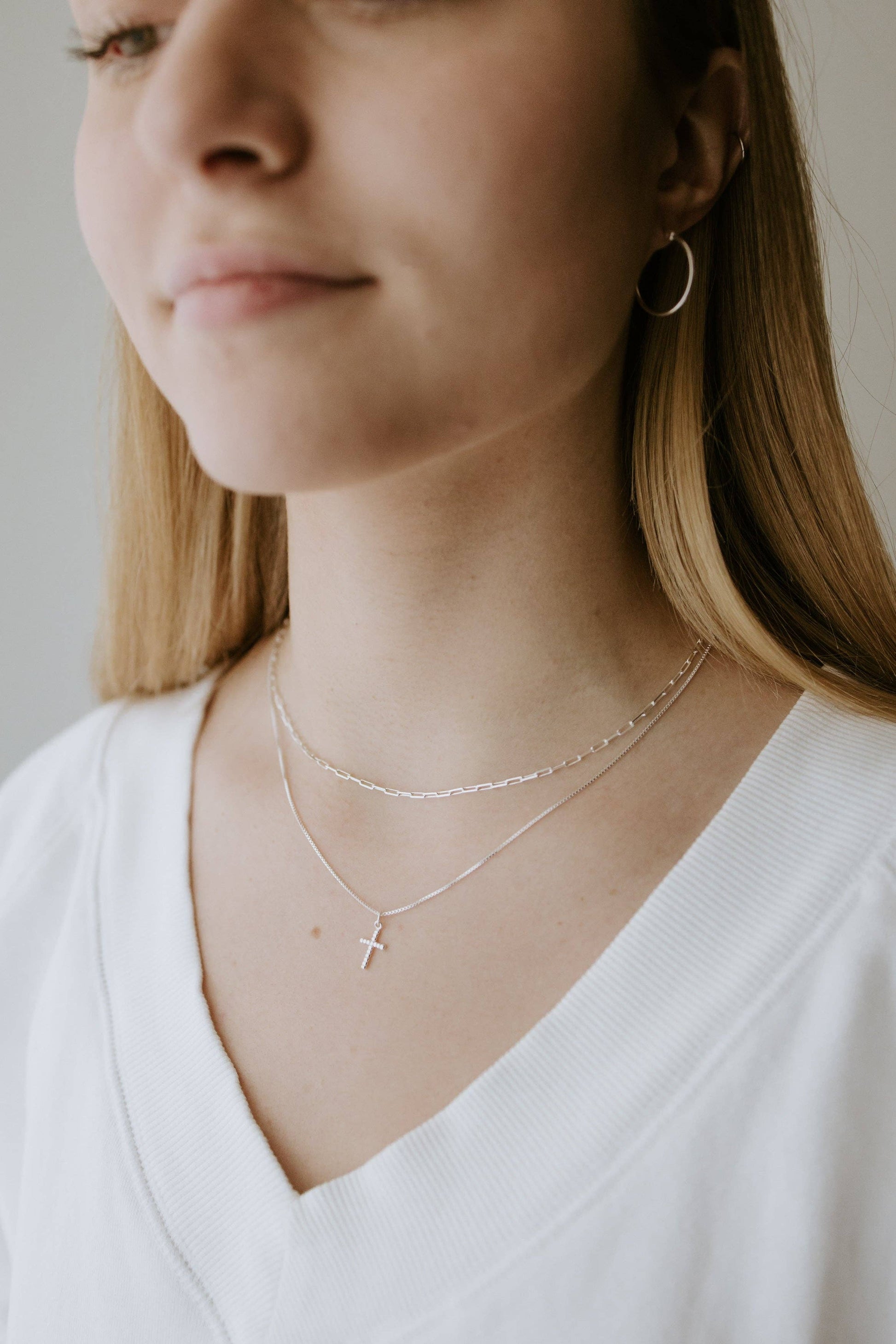 Close-up of a person wearing silver Canadian necklaces with a neutral background