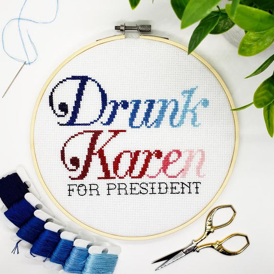 Embroidery hoop with 'Drunk Karen For President' text, surrounded by embroidery threads and scissors on a white background.