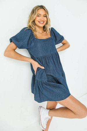 
                
                    Load image into Gallery viewer, A light weight denim mini dress featuring square neckline, short sleeve with elastic and tiered bottom Details Self: 100% Cotton Size &amp;amp; Fit - Model is 5`8&amp;quot; And Wearing Size Small - Measurements Taken From Size Small - Approx Length: 26&amp;quot;
                
            