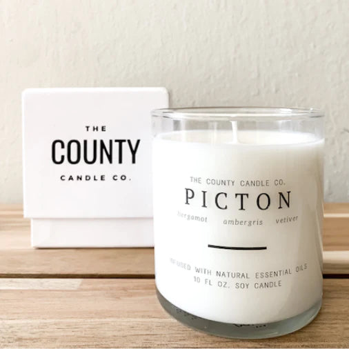 The county Candle code white soy candle in clear glass clear label simple font, Picton, large letters, white box in background, nice square lines clean the county Candle