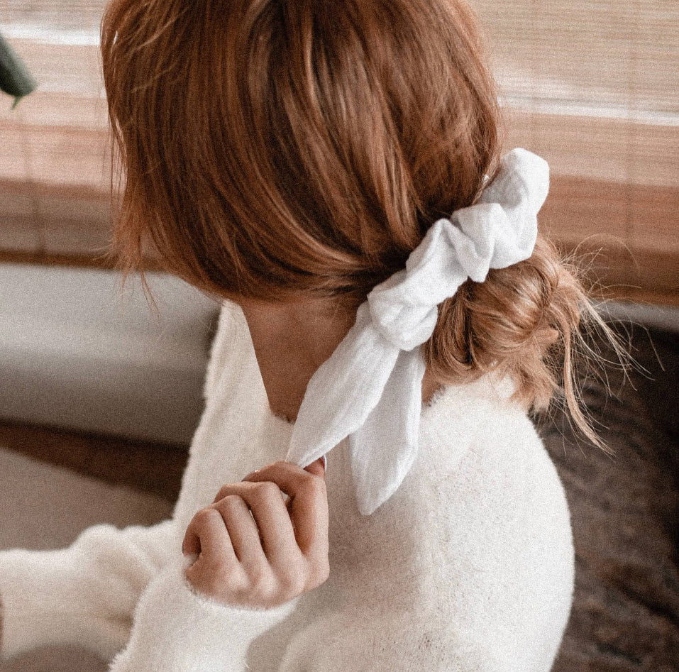 amelia rose the label canadian designer soft cotton oversize scrunchie with cute bunny tails shown in white in a simple low messy diy bun with a sofy cashmere sweater to round out the effotless look 