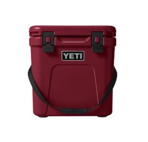 YETI Roadie 24 hard cooler with two heavy duty latches on lid and a shoulder strap in harvest red