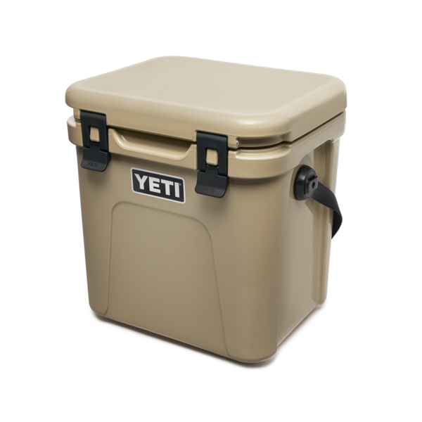YETI Roadie 24 hard cooler with two heavy duty latches on lid and a shoulder strap in tan