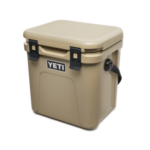 YETI Roadie 24 hard cooler with two heavy duty latches on lid and a shoulder strap in tan